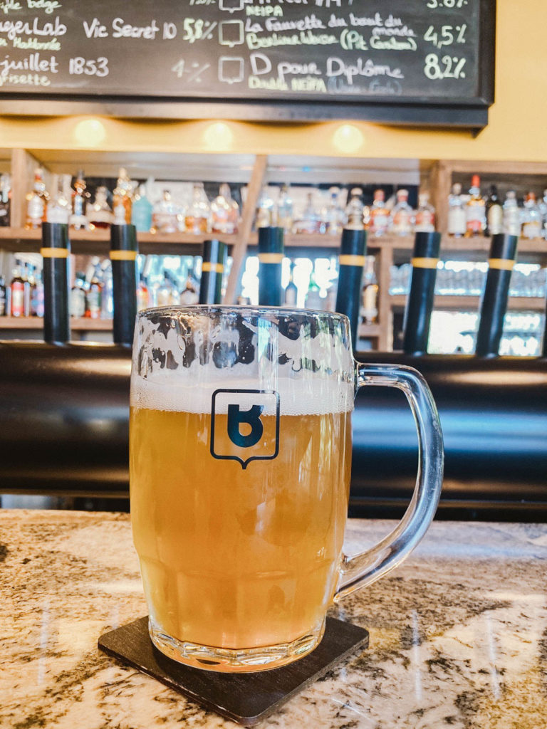 A frothy mug of beer sits on a marble countertop in a bright, airy bar setting. Including a visit to a local brewery is a fun addition to your Montreal itinerary for 2 days.